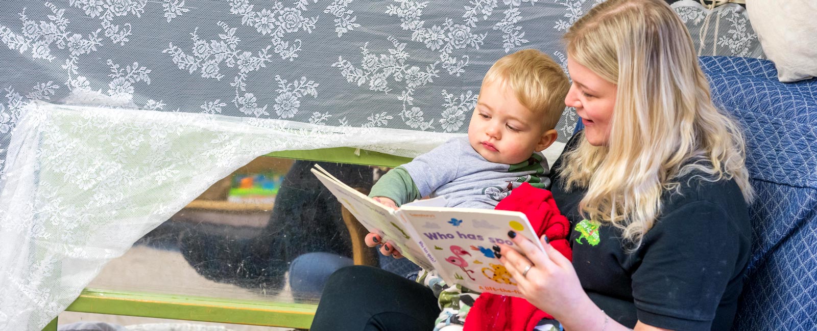 One of our childcare professionals reading with an under-five child.